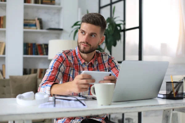 Aantrekkelijke Jongeman Die Thuis Aan Het Bureau Zit Mobiele Telefoon — Stockfoto