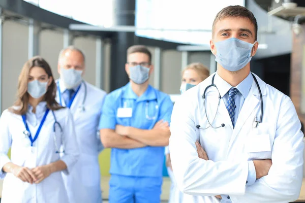 Médico masculino em máscara médica com grupo de colegas felizes e bem sucedidos também em máscaras preventivas. — Fotografia de Stock