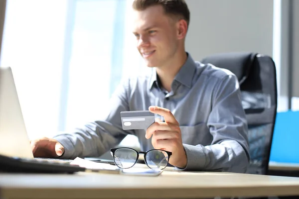 Hombre Sonriente Sentado Oficina Paga Con Tarjeta Crédito Con Computadora — Foto de Stock
