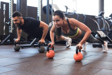 Spor salonunda şınav çeken kadın ve erkek.