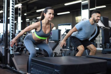 Uygun spor salonunda çömelme hareketleri yapan zinde bir çift.