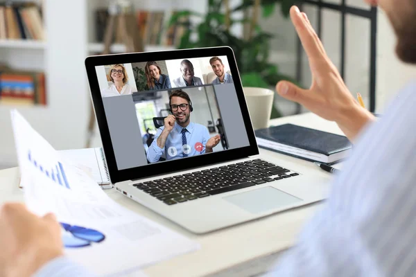 Businessman video conferencing with colleague on laptop in office.