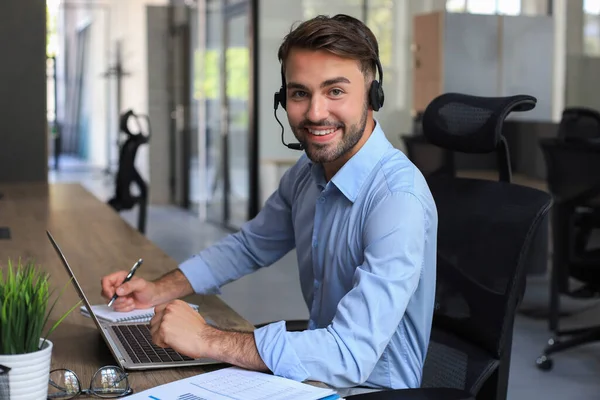 ラップトップ ヘルプサービス クライアントコンサルティングコールセンターのコンセプトを使用しながら 職場で ヘッドセットの陽気な若いサポート電話の男性オペレーター — ストック写真