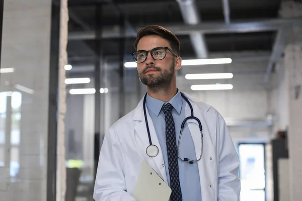 Hastane Koridorunda Yakışıklı Genç Doktor Kameraya Bakıyor Gülümsüyor — Stok fotoğraf