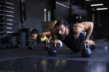 Spor salonunda şınav çeken kadın ve erkek.