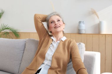 Çekici orta yaşlı kadın evdeki kanepede dinleniyor.