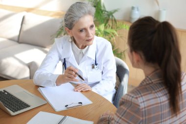 Ofisteki hastaya danışmanlık yapan orta yaşlı kadın doktor.