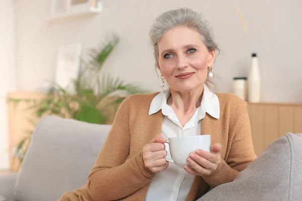 Ευτυχισμένη Ώριμη Γυναίκα Στηρίζεται Άνετο Καναπέ Ποτό Καφέ Τσάι Κοιτάζοντας — Φωτογραφία Αρχείου
