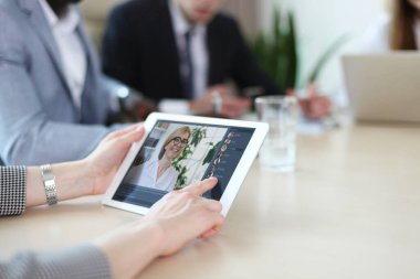 Ofiste finansal istatistikleri analiz eden insanlar toplanıyor. Bir grup iş adamı dijital tablet üzerinde ekibiyle video konferansı yapıyor..