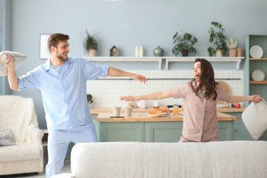 Mutlu çift oturma odasında yastık savaşı yaparken eğleniyor.