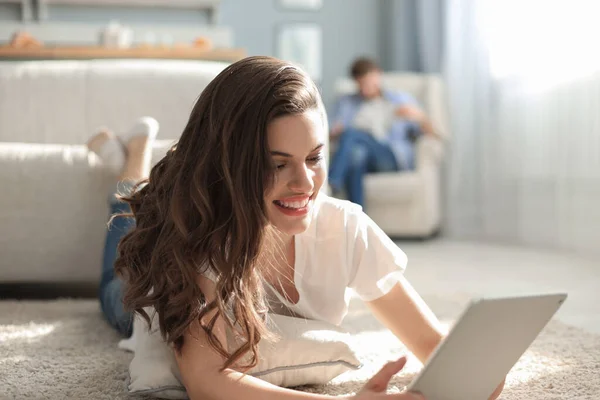 Sonriente Hermosa Mujer Usando Tableta Con Hombre Borroso Fondo Casa — Foto de Stock