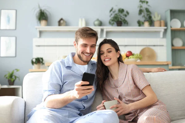 Pareja Joven Pijama Viendo Contenido Línea Teléfono Inteligente Sentado Sofá —  Fotos de Stock