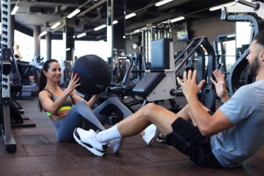Formda ve kaslı bir çift spor salonunda ilaç topuyla egzersiz yapıyor.