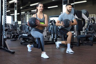 Güzel genç spor çifti jimnastik salonunda sağlık topuyla antrenman yapıyor.