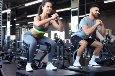 Uygun spor salonunda çömelme hareketleri yapan zinde bir çift.