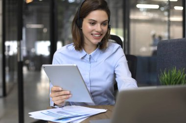 Serbest çalışan biri kulaklıklarla konuşuyor ve ofisteki müşterilere danışıyor.