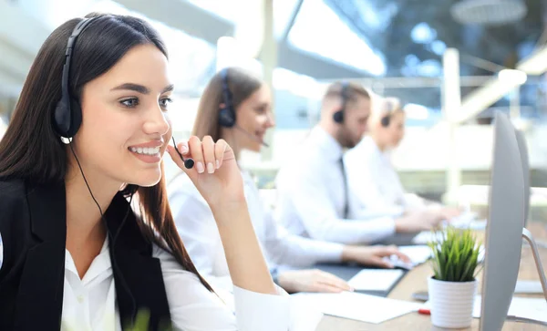 Portret van callcenter medewerker vergezeld door haar team. Lachende klant support operator aan het werk. — Stockfoto