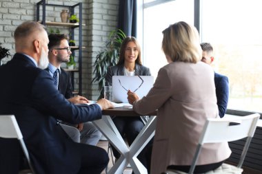 İş adamlarından oluşan bir ekip yaratıcı ofiste masada tartışıyor.