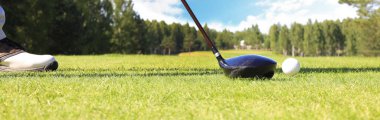 Golf oyuncusu yeşil topu deliğe sokuyor.