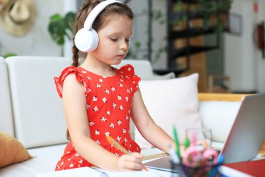 Mesafe öğrenme. Çevrimiçi e-öğrenme sisteminde çalışırken dizüstü bilgisayar kullanan neşeli küçük kız