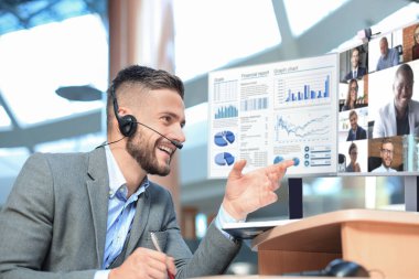 İş adamı video konferansında iş arkadaşlarıyla konuşuyor. Bilgisayarlı bilgisayar kullanarak şirketlerinin mali raporlarını tartışan çok ırklı iş adamları..