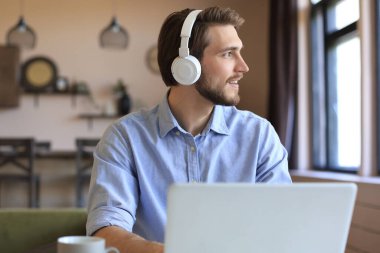 Kulaklık takan kendine güvenen bir adam konuşuyor ve iş kıyafetleri eğitimi izliyor, konferans dinliyor.