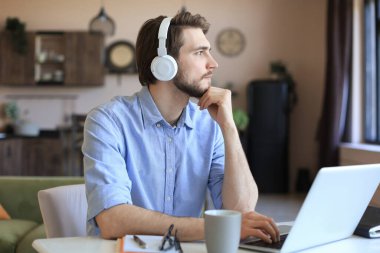 Kulaklık takan kendine güvenen bir adam konuşuyor ve iş kıyafetleri eğitimi izliyor, konferans dinliyor.