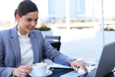 Başarılı bir iş kadınının portresi bir şeyler yazıyor ve restoranda otururken gülümsüyor.