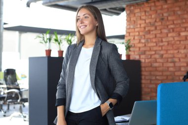 Ofiste dururken gülümseyen çekici bir iş kadını.