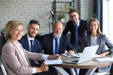 İş adamlarından oluşan bir ekip yaratıcı ofiste masada tartışıyor.