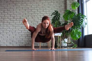 Sağlıklı bir hayat. Çekici bir kadın evde yoga yapıyor, spor kıyafetleri giyiyor.