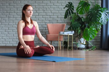 Lotus poz verip yoga stüdyosunda meditasyon yapan güzel bir kadın.