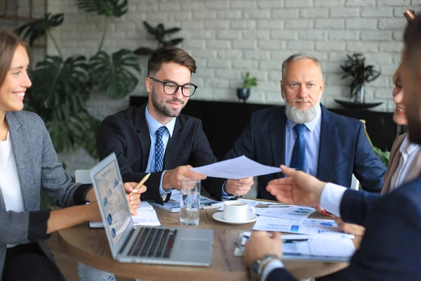 İş adamlarından oluşan bir ekip yaratıcı ofiste masada tartışıyor.