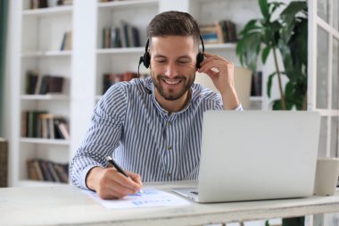 Ofiste otururken dizüstü bilgisayar kullanan düşünceli bir iş adamı.