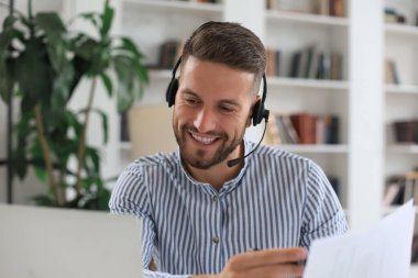 Gülümseyen genç iş adamı ofiste video görüşmesi yapıyor.