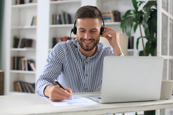 Ofiste otururken dizüstü bilgisayar kullanan düşünceli bir iş adamı.