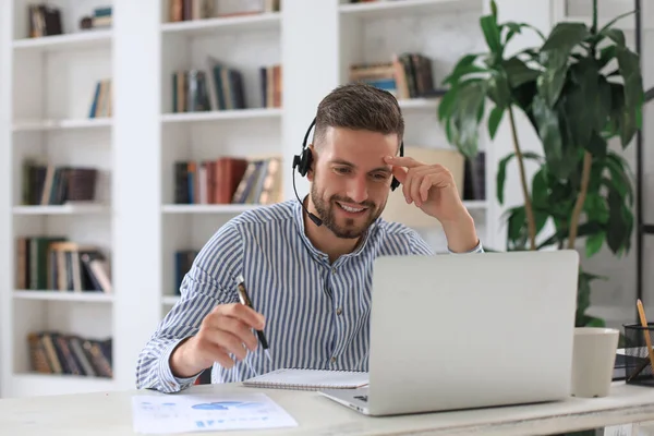 Gülümseyen genç iş adamı ofiste video görüşmesi yapıyor.