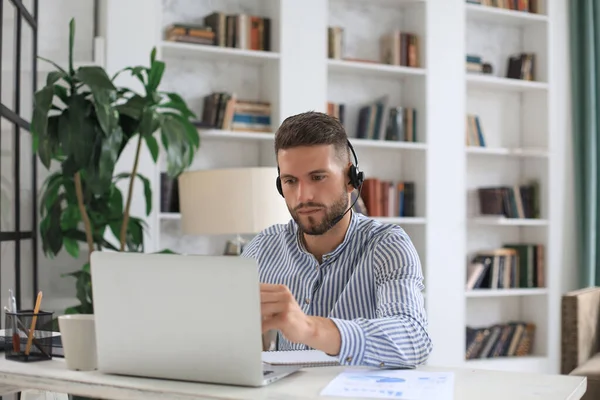 Ofiste otururken dizüstü bilgisayar kullanan düşünceli bir iş adamı.