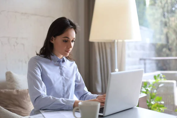 Jolie femme assise à table, regardant l'écran de l'ordinateur portable. Heureux entrepreneur lire message email avec de bonnes nouvelles, bavarder avec les clients en ligne. — Photo