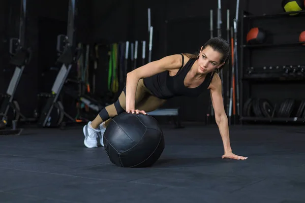 Donna in forma e muscolosa che si allena con la palla medica in palestra. — Foto Stock