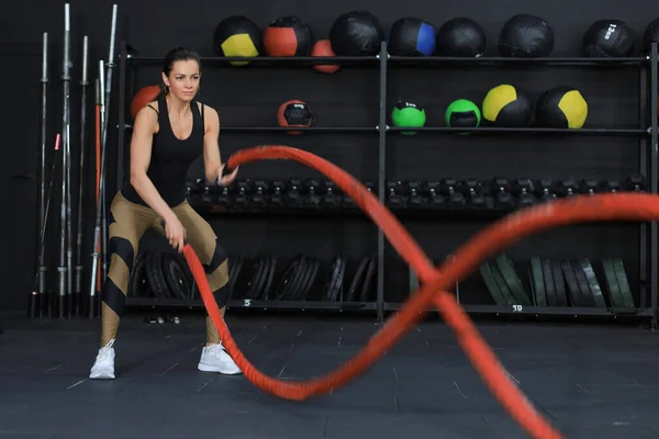 Fit vrouw met behulp van battle touwen tijdens krachttraining in de sportschool. — Stockfoto