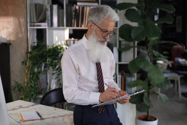 Konzentrierter Reifer Geschäftsmann Der Seinem Modernen Büro Arbeitet Und Notizen — Stockfoto