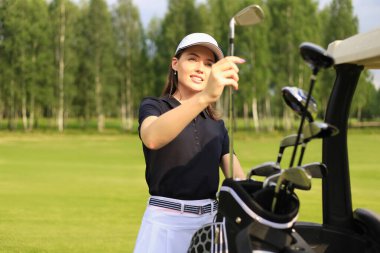 Profesyonel kadın golfçü çantadan golf sopasını seçiyor.