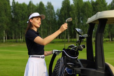 Profesyonel kadın golfçü çantadan golf sopasını seçiyor.