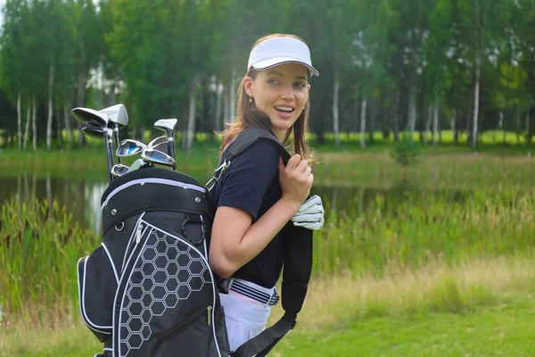 Beautiful golf woman player carrying a golf bag and smiling