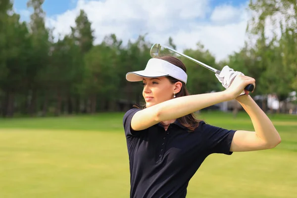 Woman golfer hits an fairway shot towards the club house