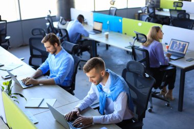 Ofiste çalışırken borsa verilerini analiz eden modern iş adamları.