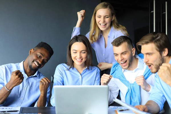 Щасливі ділові люди сміються біля ноутбука в офісі. Успішні колеги по команді жартують і розважаються разом на роботі . — стокове фото