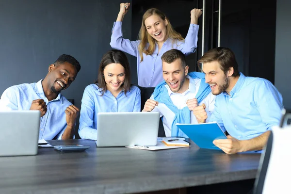 Gelukkige zakenmensen lachen in de buurt van een laptop op kantoor. Succesvolle team collega 's grap en veel plezier samen op het werk. — Stockfoto