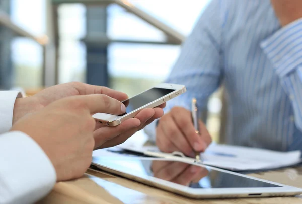 Smartphone ręki w zbliżenie, kolegów pracujących w tle. — Zdjęcie stockowe